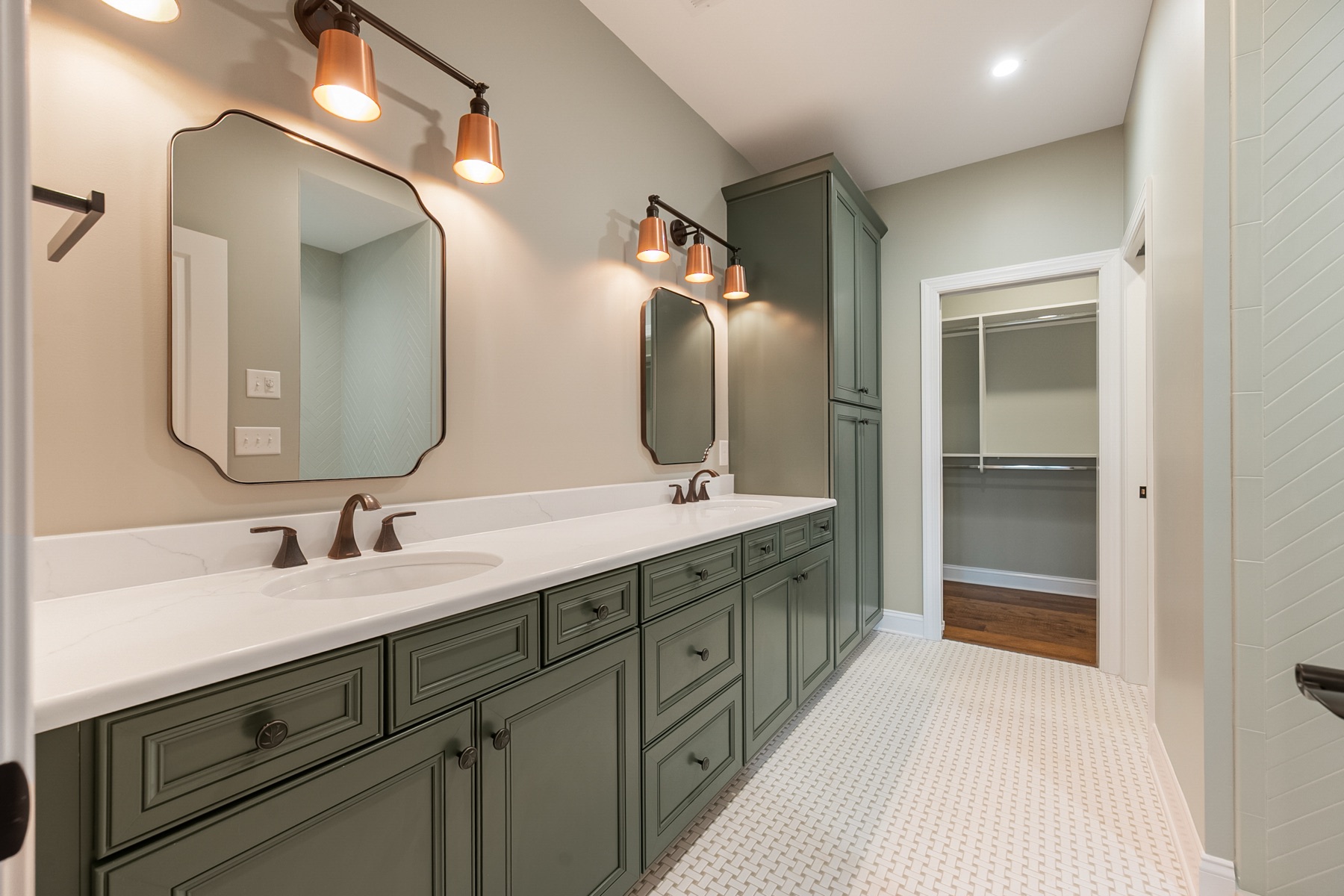 The Aspen - primary bathroom with sage green custom cabinets, quartz counters, and brass sconces